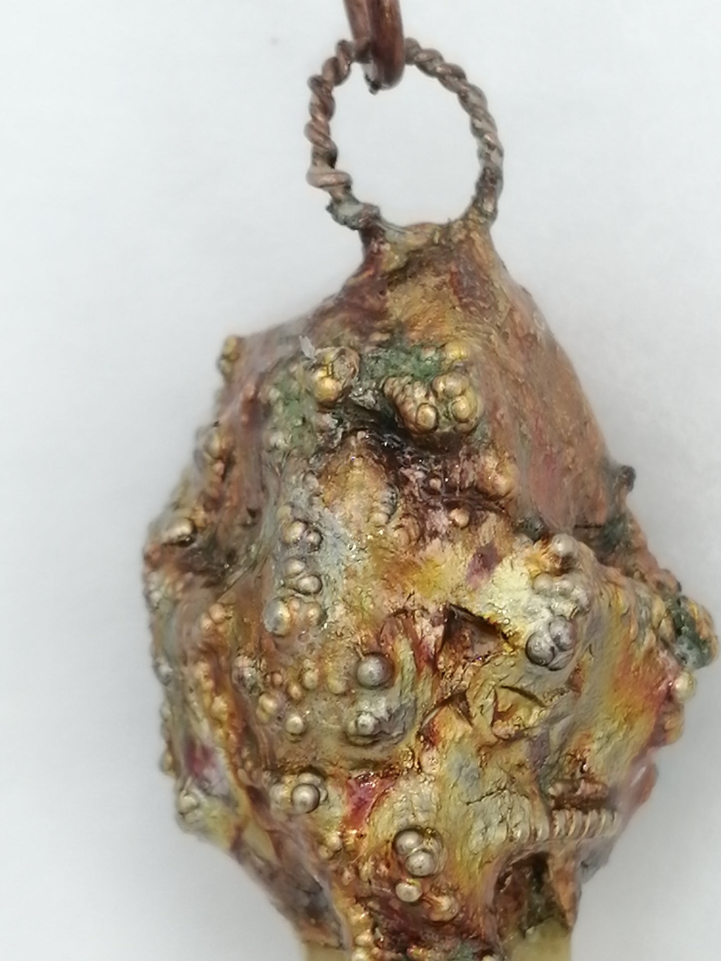 electroformed copper pendant with enclosed clinohumite crystal with iridescent patina